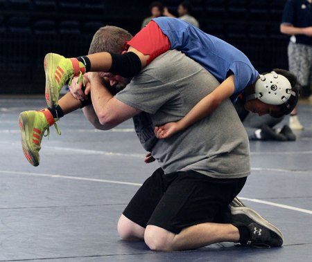 Coach James McDonald shows a young wrestler a move.